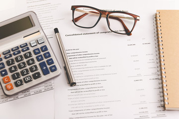 Calculators, pens and glasses placed on financial analysis documents