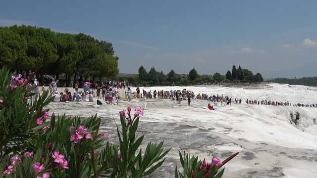 Pamukkale, Denizli, Turkey - 16th of July 2019: 4K Train of tourists on the sinter terraces