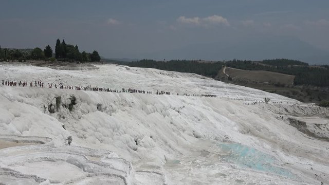 Pamukkale, Denizli, Turkey - 16th of July 2019: 4K Viewing long train of tourists walking on the sinter terraces