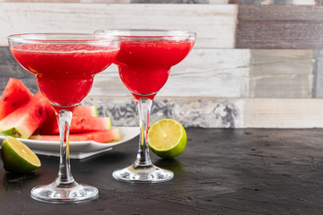Two watermelon smoothies with slices of watermelon, lemon and lime