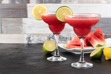 Two watermelon smoothies with slices of watermelon, lemon and lime