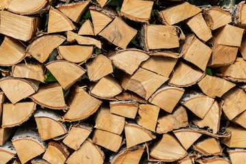 Woodpile from chopped birch firewood with bark and knots