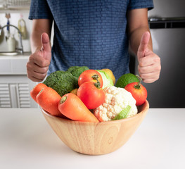 The man holds the thumb for the vegetables and fruits placed before him.