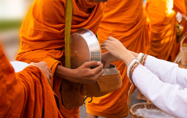 Thai people make merit by giving food to monks.