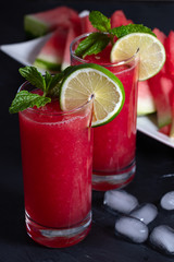 Two watermelon smoothies with lemon, lime, ice and slices of watermelon