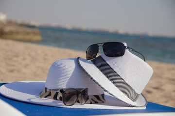 composition with hat and sunglasses on the beach background