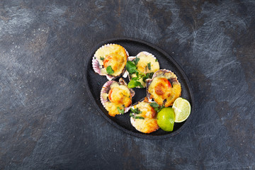 Baked seafood shellfish scallops with cheese and lemon. black background