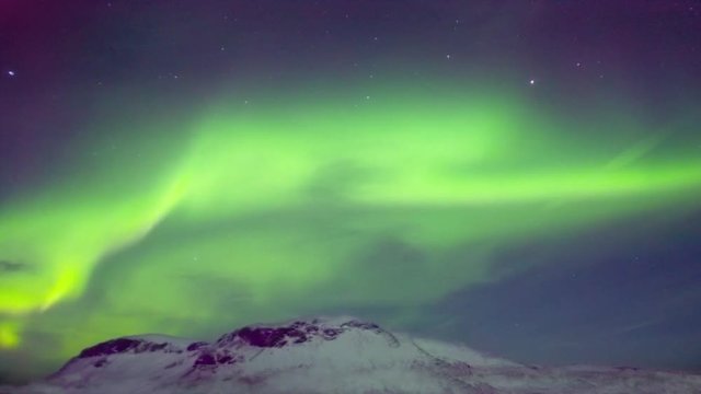 Bright aurora over mountain winter landscape, timelapse.