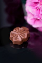 Luxury chocolate candies flowers and pink hydrangea on a black reflective background, copy space