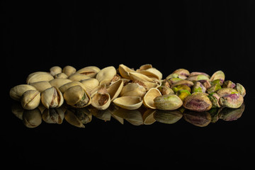Lot of whole lot of pieces of ripe green pistachio isolated on black glass