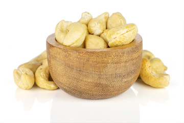 Lot of whole unsalted beige cashew in tiny wooden bowl isolated on white background