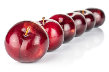 Group of six whole ripe red round plum placed diagonally in line isolated on white background