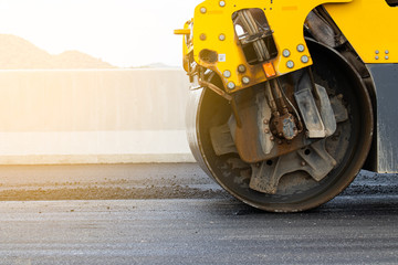 Asphalt road surface is smoothed with steel wheels, road construction machinery, asphalt paver - obrazy, fototapety, plakaty