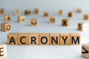 acronym - word from wooden blocks with letters, use of acronyms in the modern world abbreviation concept, random letters around, top view on wooden background