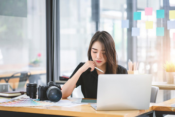 Young Asian graphic designer working on computor and graphics tablet in her working space