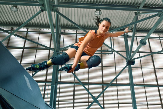 Rollerblader jump high from big air ramp performing trick. Indoors skate park equipment.