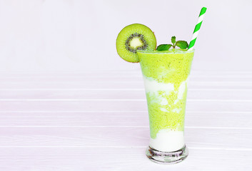 Kiwi yogurt fruit juice smoothie and green kiwi juice drink healthy, delicious taste in a glass for weight loss on a white wooden background.
