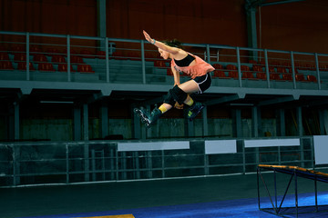 Rollerblader jump high from big air ramp performing trick. Indoors skate park equipment.