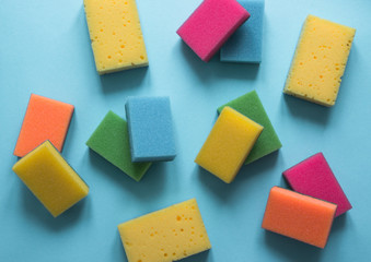 on a blue background lies a layout of different color sponges for cleaning the kitchen cleaning dishes