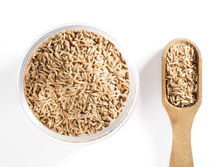 Cumin seeds (Cuminum), Jeera in a glass cup and wooden scoop on a white background