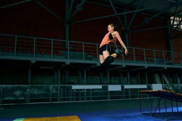 Rollerblader jump high from big air ramp performing trick. Indoors skate park equipment.