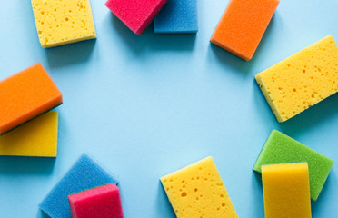 on a blue background lies a layout of different color sponges for cleaning the kitchen cleaning dishes