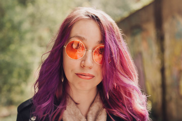 Woman in orange sunglasses and with colorful dyed hair.