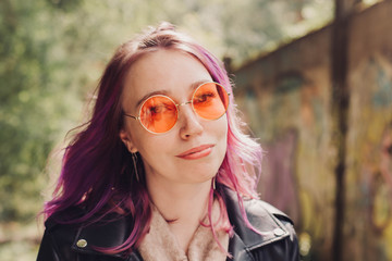 Woman in orange sunglasses and with colorful dyed hair.