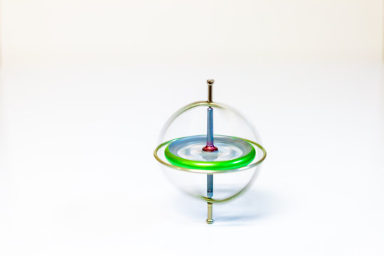 A spinning metal toy gyroscope isolated on a white background