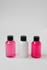 Mini bottles of pink and white color with body care cosmetics or hair on white background. Improvement of the hotel. Copy space