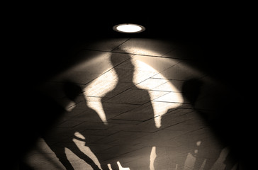 Group of People, silhouettes and shadows on a wall, light by lamp or floodlight on old wall with shadows, concept picture