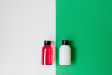 Set of cosmetic products for shower or bath, white and pink bottles on white and green background. Copy space