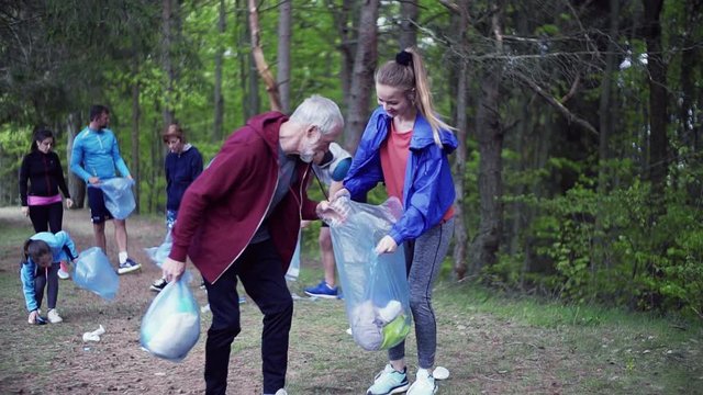 Group of fit people picking up litter in nature, a plogging concept.