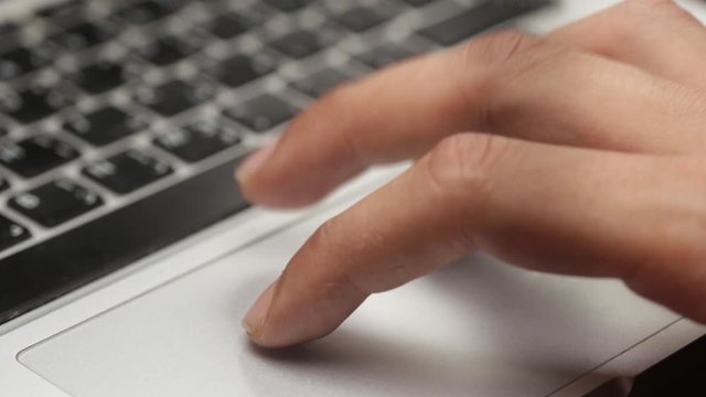 closeup of a man's hand using the trackpad on a laptop 