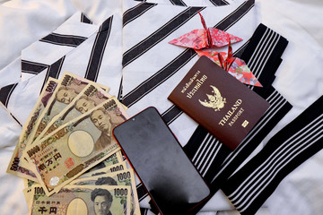 Passport,mobile phone,banknotes, credit card and origami paper birds place on japanese pajamas call...
