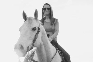 Western lifestyle image of woman horseback riding, vintage style black and white.