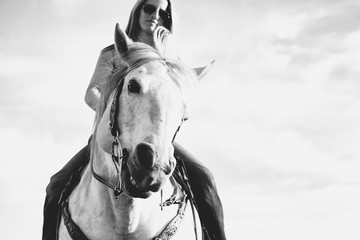 Obraz premium Black and white horseback riding concept with horse head close up and portrait of rider.