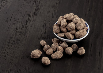 Okinawan black sugar in small dish on wood background