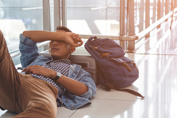 Traveler waiting at the airport departure area for his delay flight.  Young traveler sleeping on...
