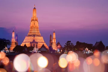 Poster Wat Arun temple with sunset and blur bokeh at foreground during sunset. © BUSARA