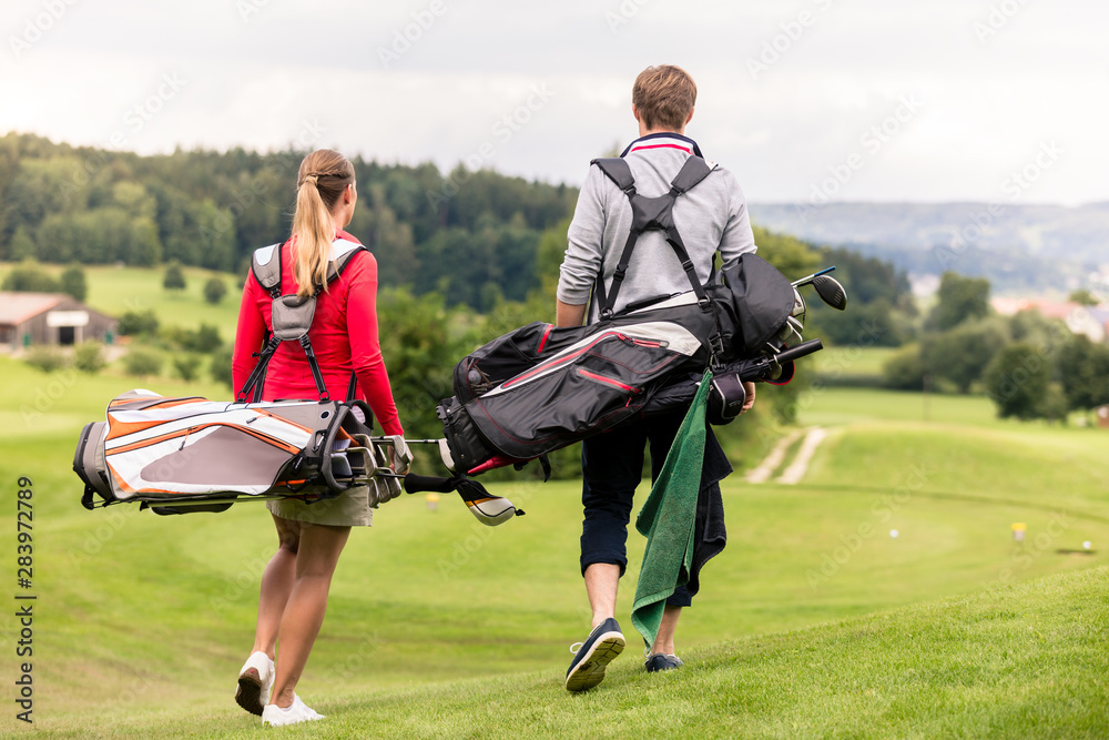 Wall mural rear view of couple carrying golf bag