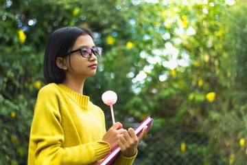 Young asian girl reading notebook at the green garden.