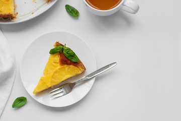 Sliced upside down pineapple cake decorated green leaves with cup of tea on white table. Summer tropical dessert. Top view. Copy space