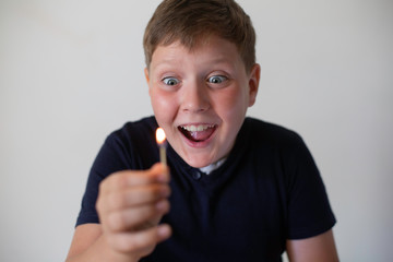 Boy pyromaniac looking to the fire match. Concept of pyromania