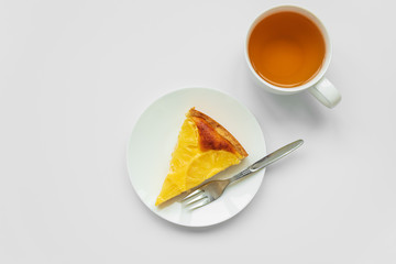 Sliced upside down pineapple cake with cup of tea on white table. Summer tropical dessert. Top view. Copy space