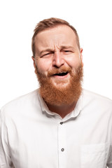 Portrait of a young, chubby, redheaded man in a white shirt making faces at the camera, isolated on a white background