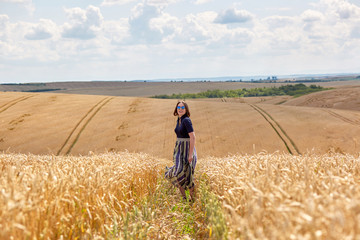 Beautiful young woman in a field of wheat dressed in a stylish dress.