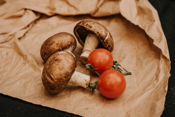 Champignons mushrooms and cherry tomatoes on black background