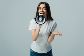 young pretty woman speaking in megaphone isolated on grey