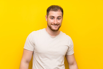 Handsome man over yellow background having doubts and with confuse face expression